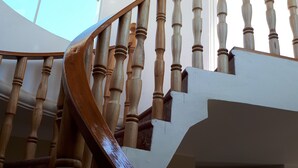 Una escalera de madera con un diseño curvo que conduce a una habitación con techo de ladrillo y un ventanal grande.