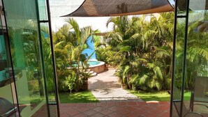 Un patio con vistas a una piscina rodeada de abundante vegetación.