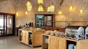 Une cuisine spacieuse, dotée de meubles en bois, d’un buffet et de luminaires suspendus.