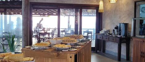 A spacious dining area with a central island, wooden furniture, and hanging rattan lamps.
