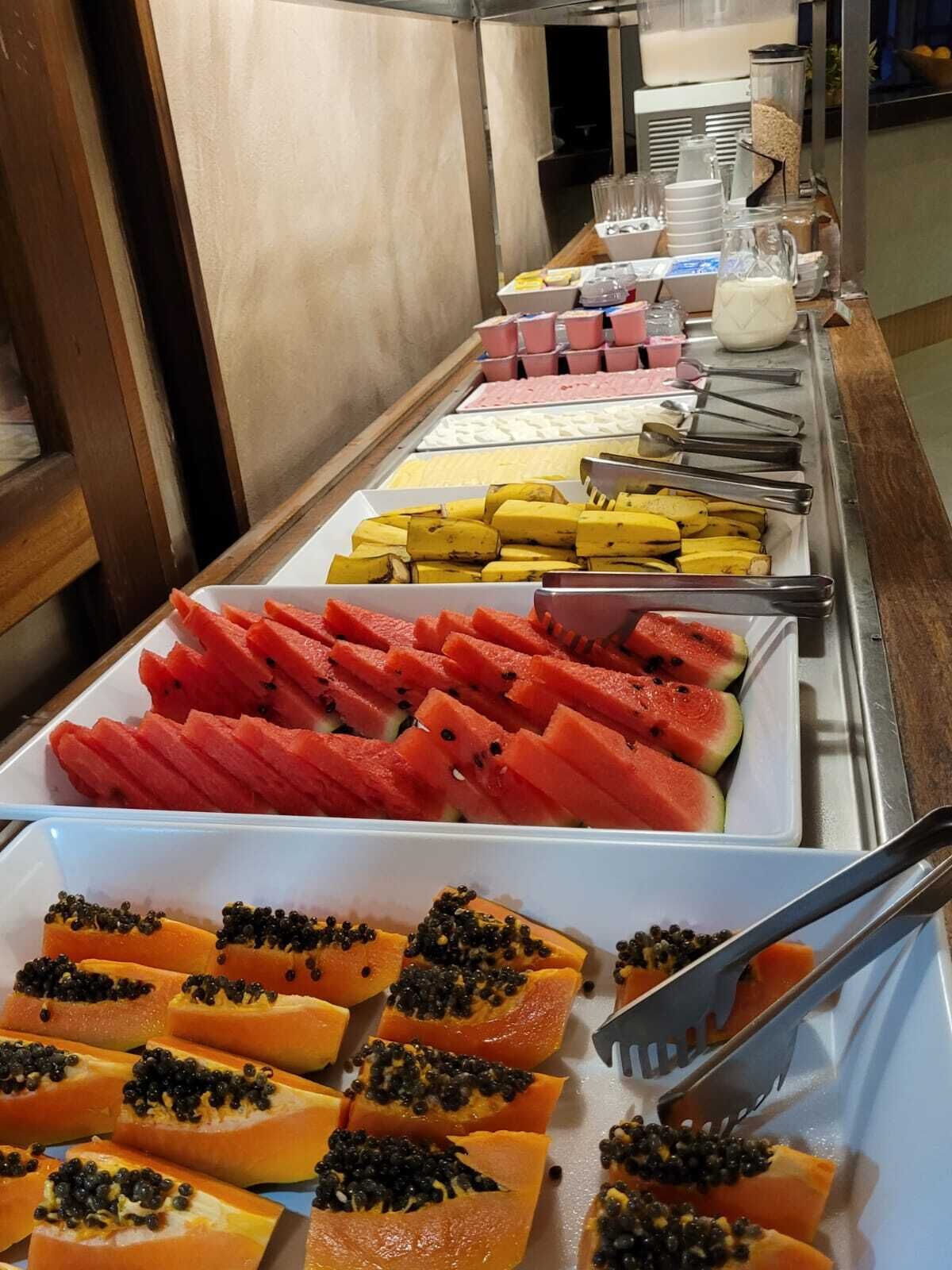A buffet with various fruits and a beverage station.