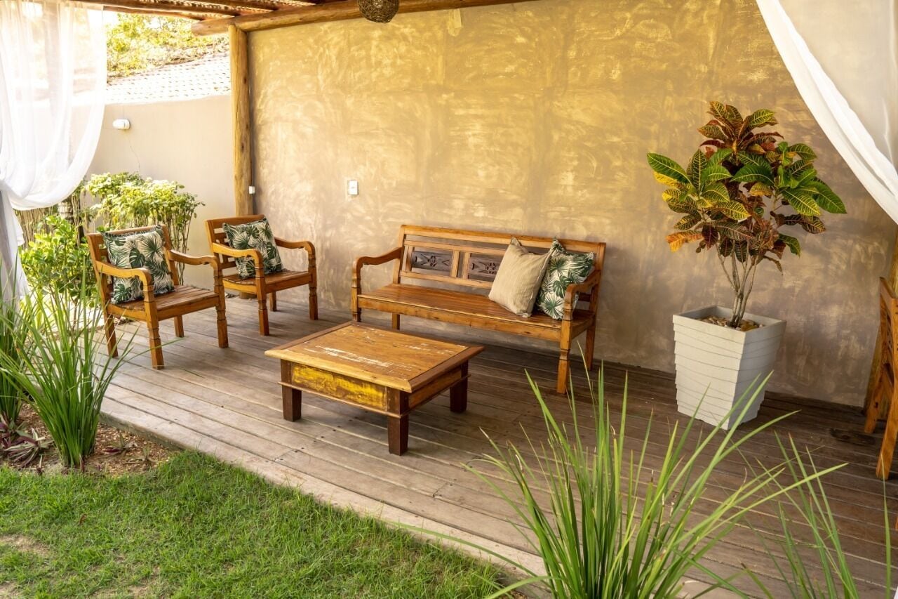 Une terrasse en bois avec un canapé, deux fauteuils et une table basse.