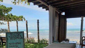 Une terrasse en bois avec un lit, un panneau indiquant les services proposés et une vue sur la mer.