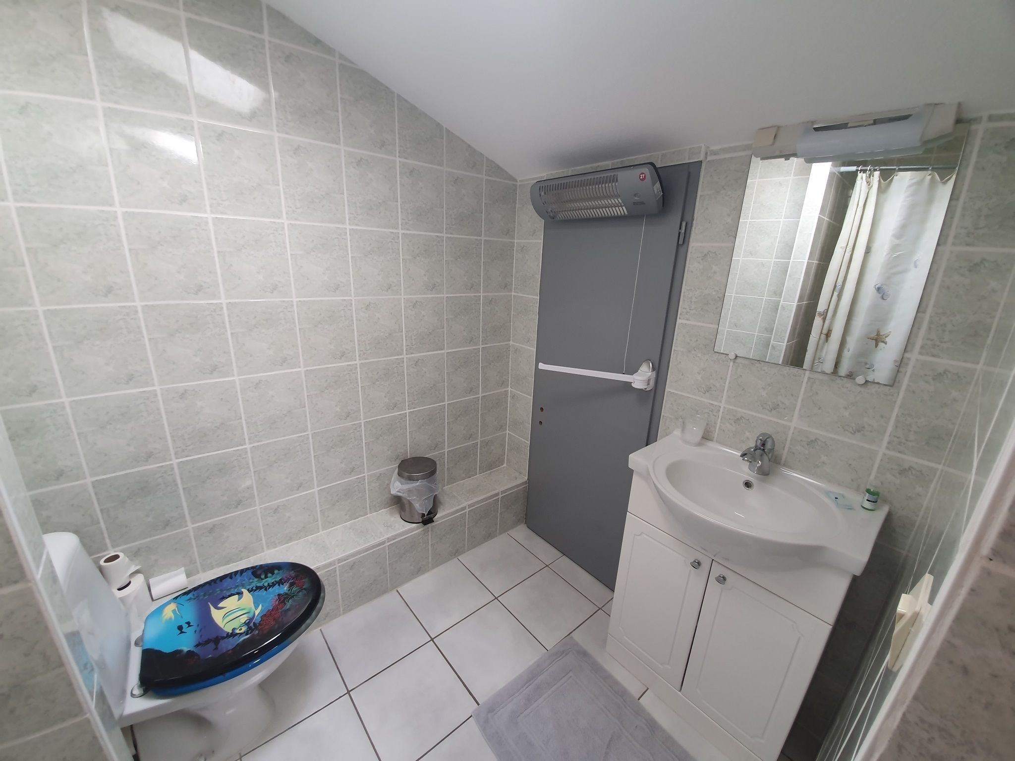 Un bagno con il water, lavabo, specchio e doccia.
