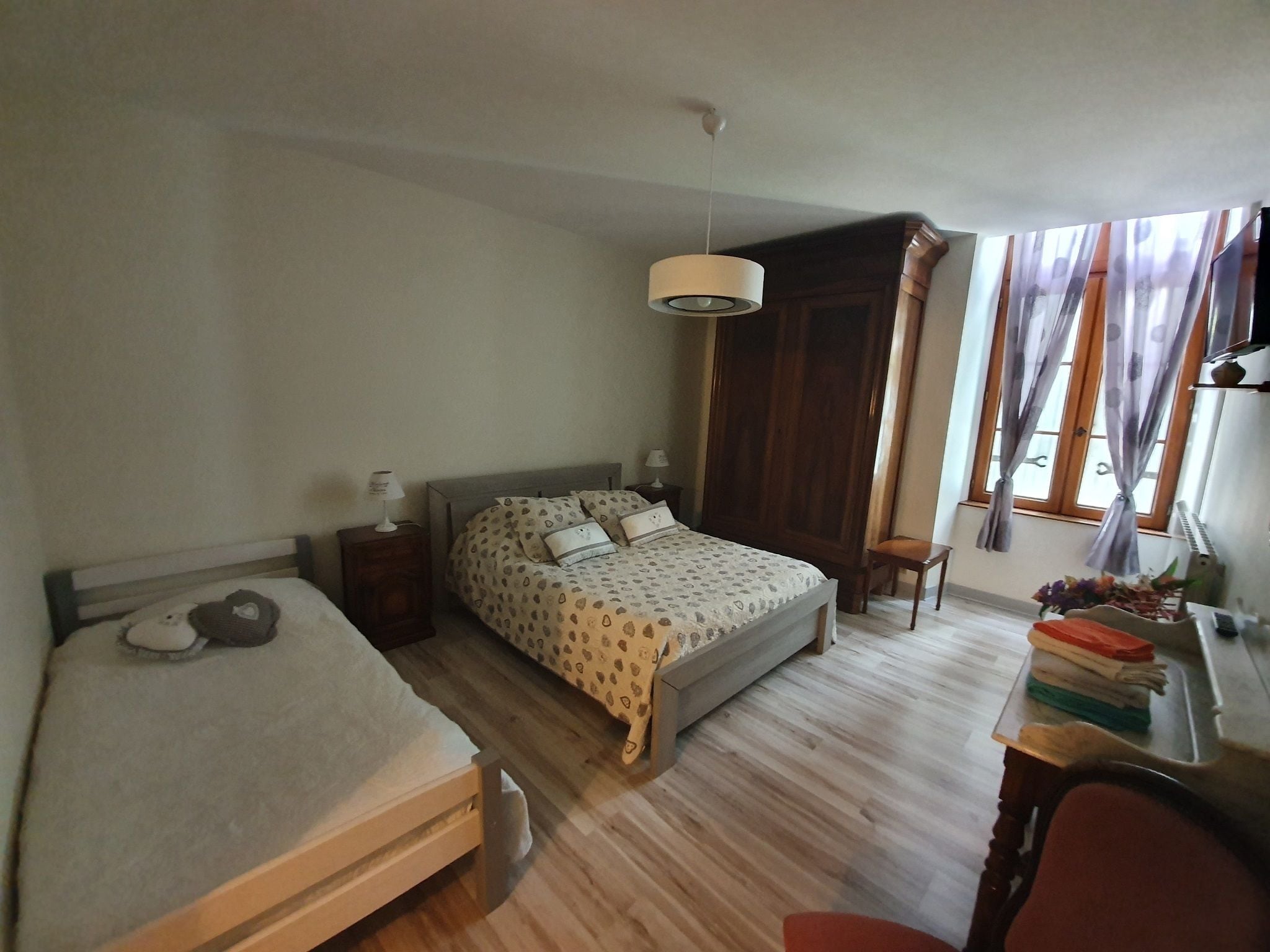 A bedroom with a bed, bedside tables, a desk, and a chair.