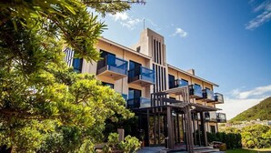 A modern multi-story building with balconies, surrounded by lush greenery and a clear sky. - Siangge Chuanfan Rock Resort (Hengchun)