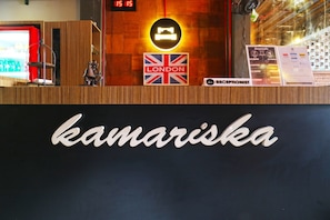 A reception desk with a sign reading "kamariska" and a British flag. - Kamariska Hostel (Sidoarjo)
