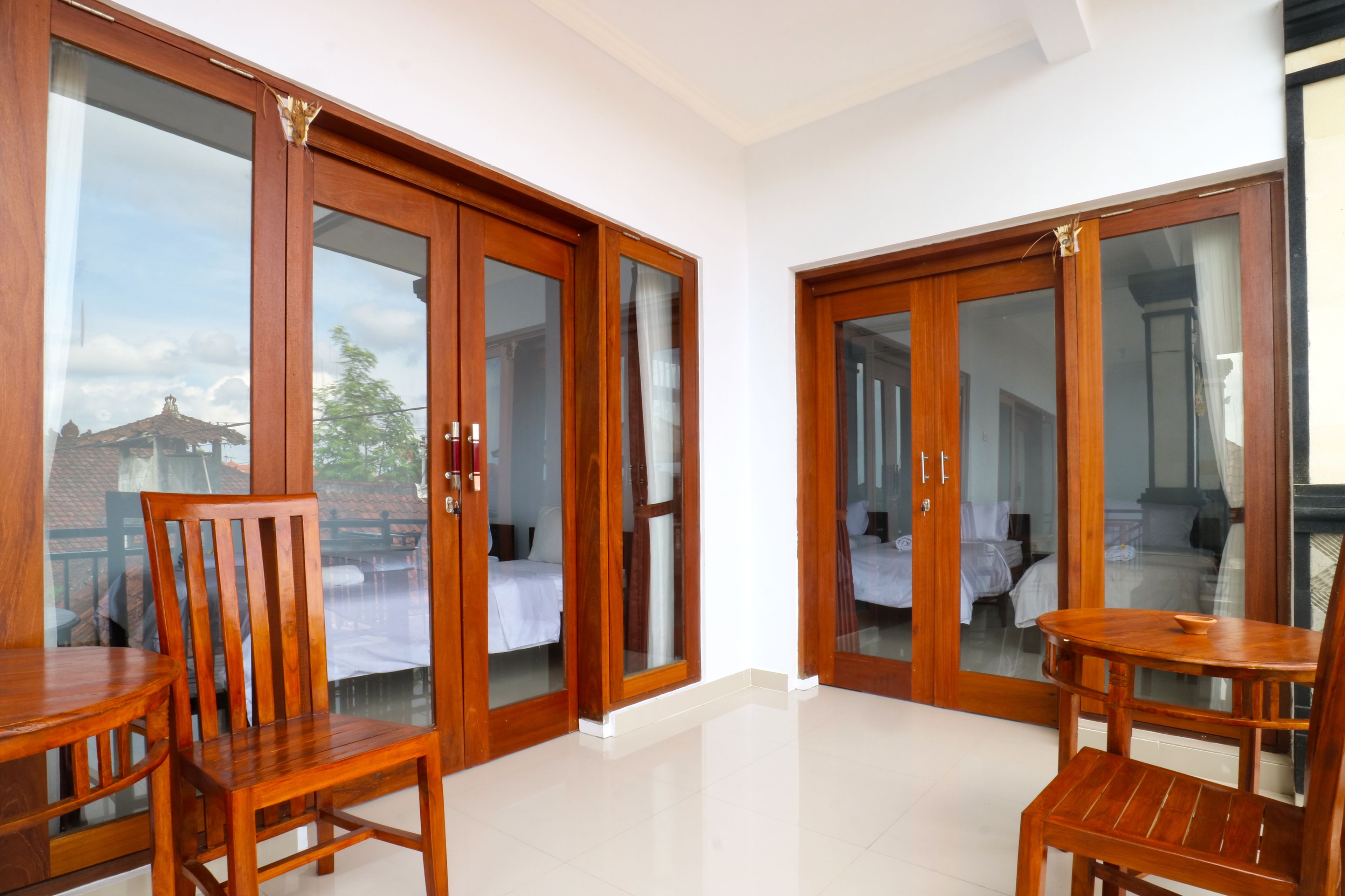 A room with a wooden table and chairs, a bed, and a sliding glass door leading to an outdoor area.