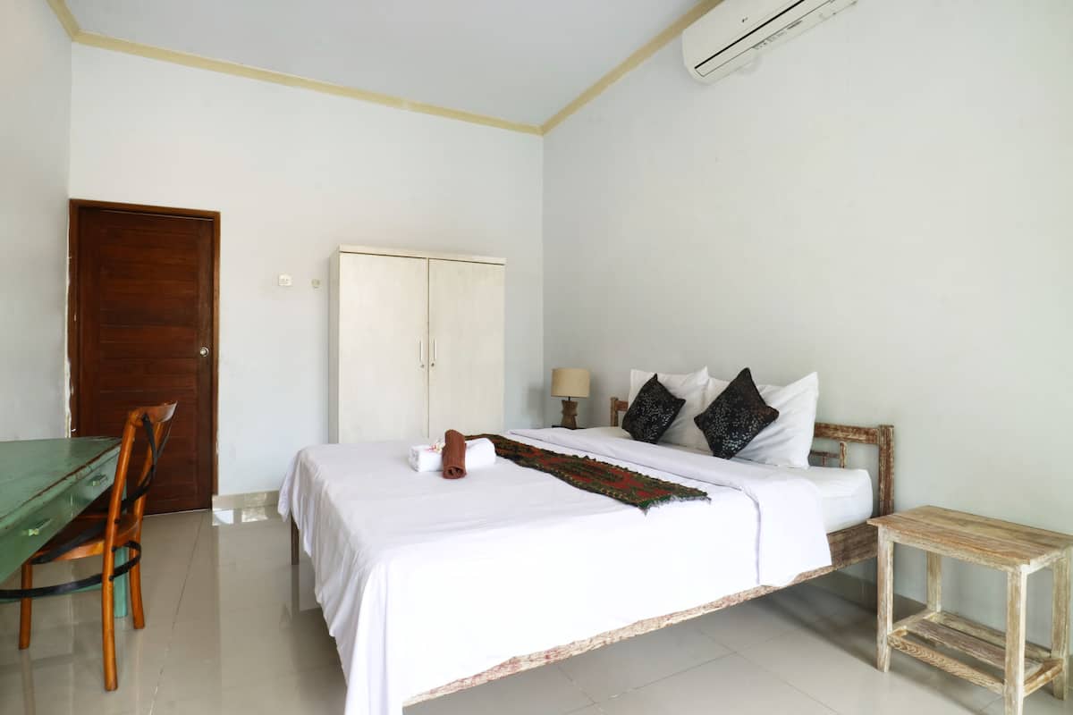 A room with a bed, a wooden chair, a small table, and a wardrobe.