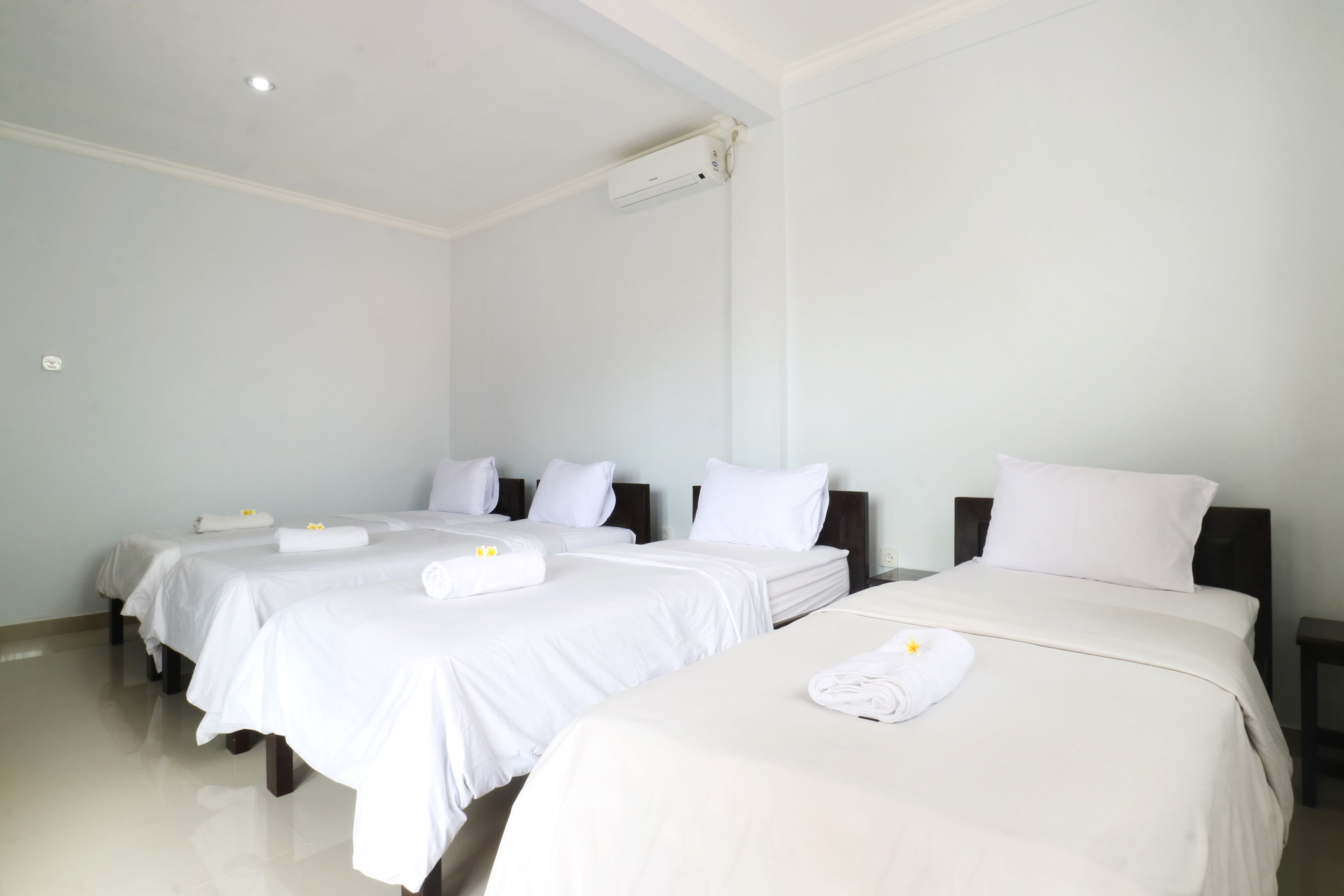 Une chambre d’hôtel avec quatre lits, chacun étant équipé de draps et de serviettes blancs.