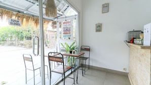 A closed restaurant with metal chairs and a wooden table, a sign indicating closure, and a view of the street outside. - The Wina Echo Beach Guesthouse (Canggu)