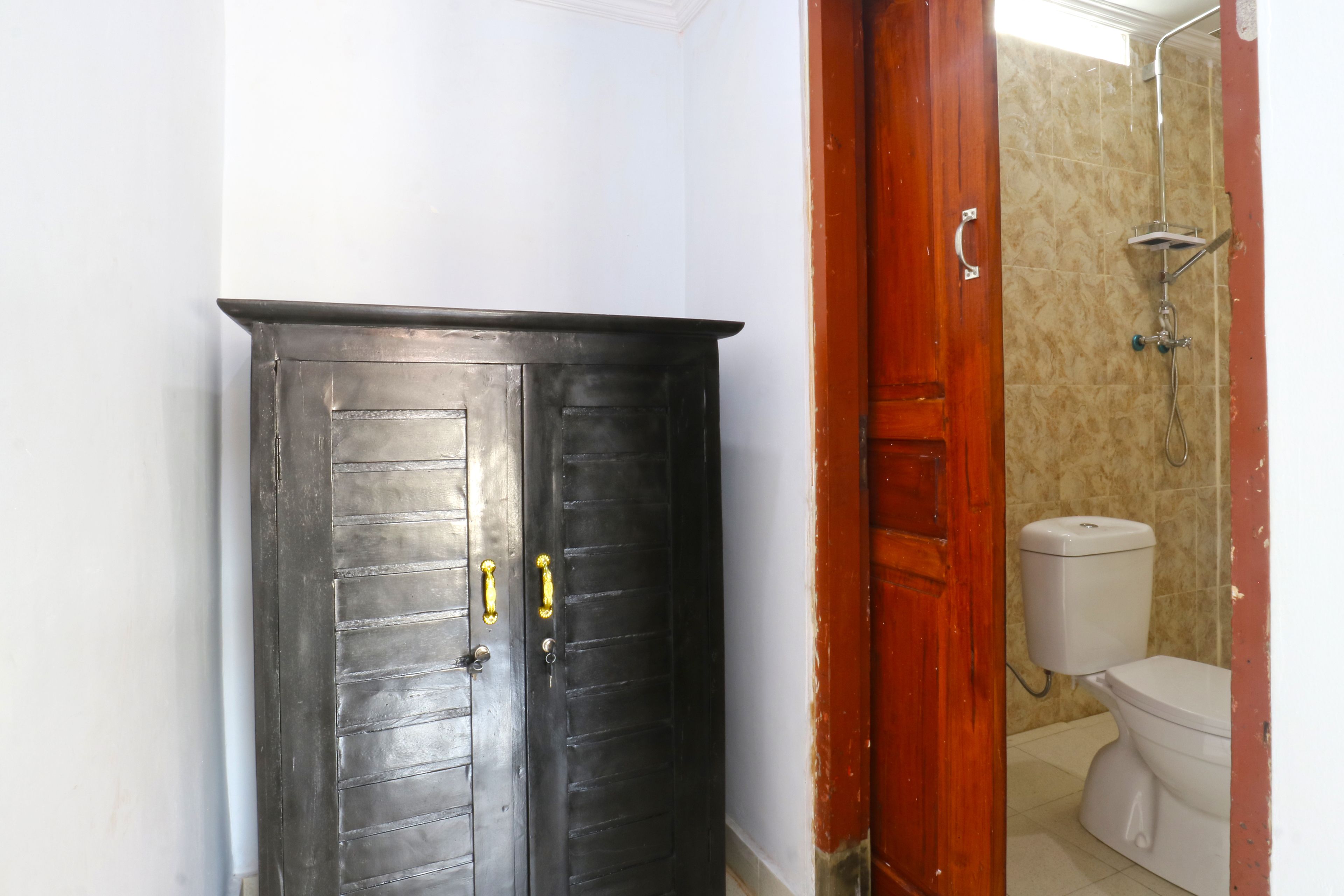 A bathroom with a toilet, shower, and a door with a handle.