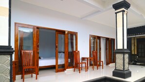 A hotel lobby with wooden furniture, a reception desk, and a staircase leading to the upper floor. - The Wina Echo Beach Guesthouse (Canggu)