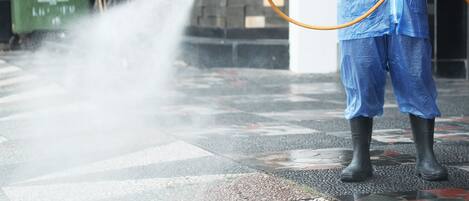 A person in protective gear using a hose to spray water.