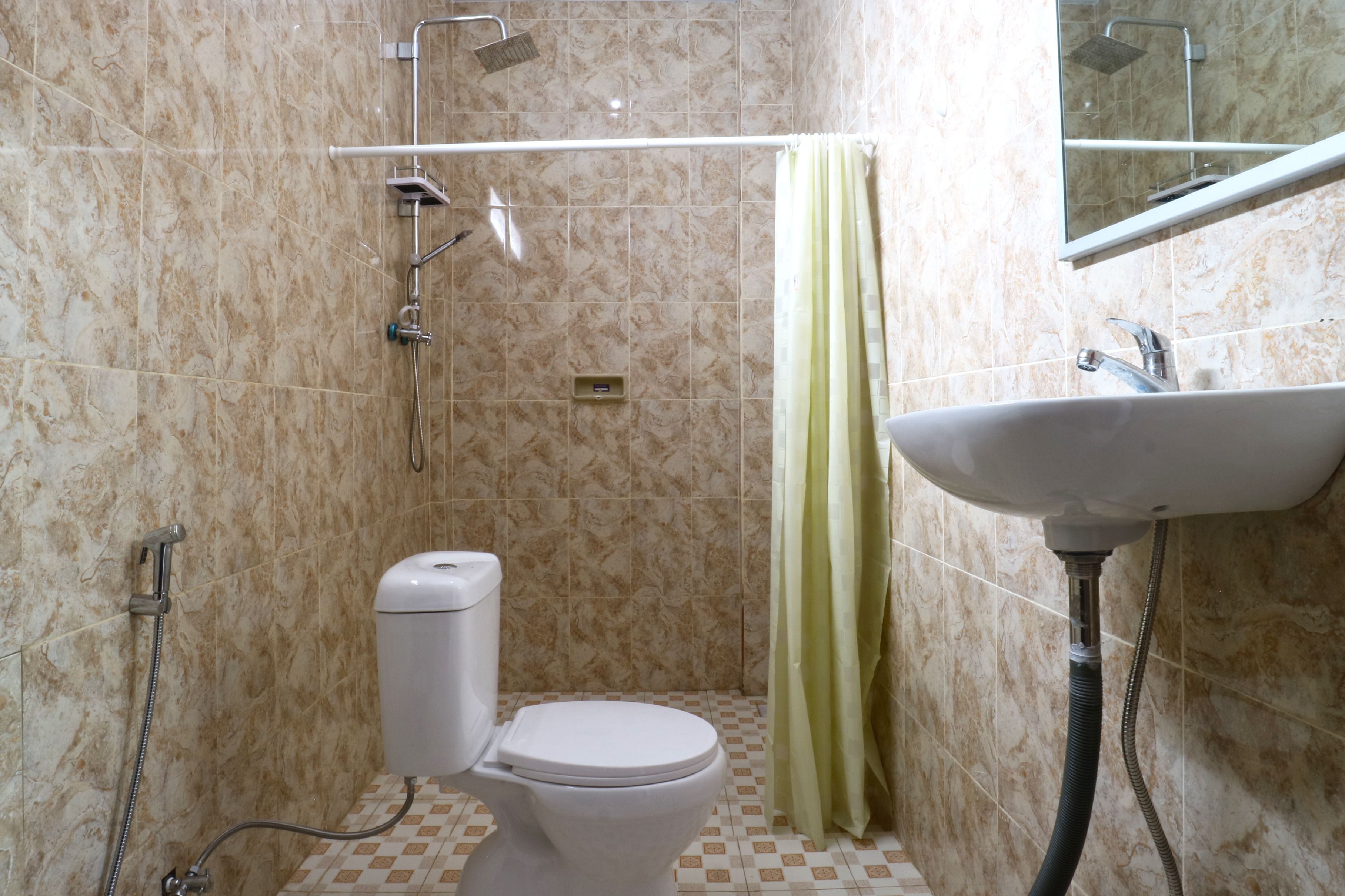 A bathroom with a toilet, shower, and sink.