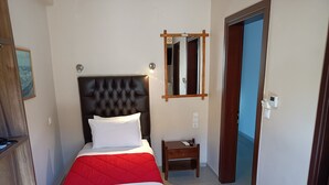 Una habitación de hotel con cama, mesita de noche, espejo y puerta.
