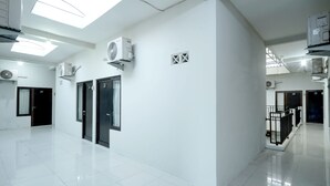 A spacious, well-lit hallway with white walls, multiple doors, and ceiling fans. - D' Paragon Bulusan (Semarang)
