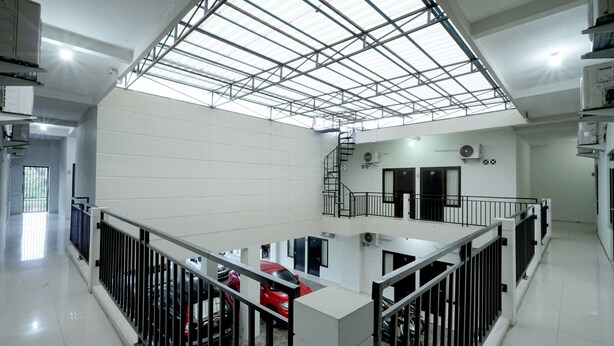 A spacious indoor area with a high ceiling, a central staircase, and a red car parked in the middle. - D' Paragon Bulusan (Semarang)