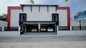 A building with a white facade, red accents, and a covered parking area with three cars. - D' Paragon Bulusan (Semarang)