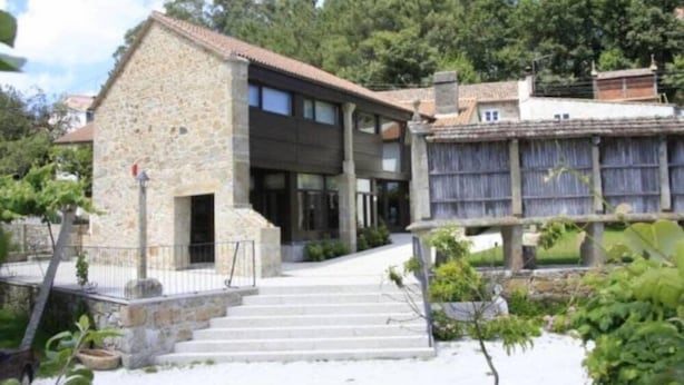 A stone building with a modern design, featuring a staircase leading to a covered entrance.