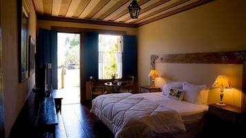 A bedroom with a bed, bedside lamps, a window with curtains, a desk, and a chair.