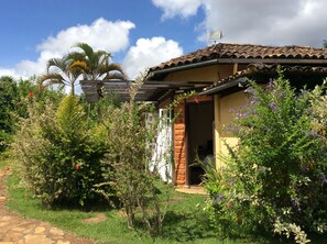 A rustic house with a tiled roof, a wooden door, and a small garden with various plants and flowers. - Paço do Lavradio Pousada (São João del Rei)