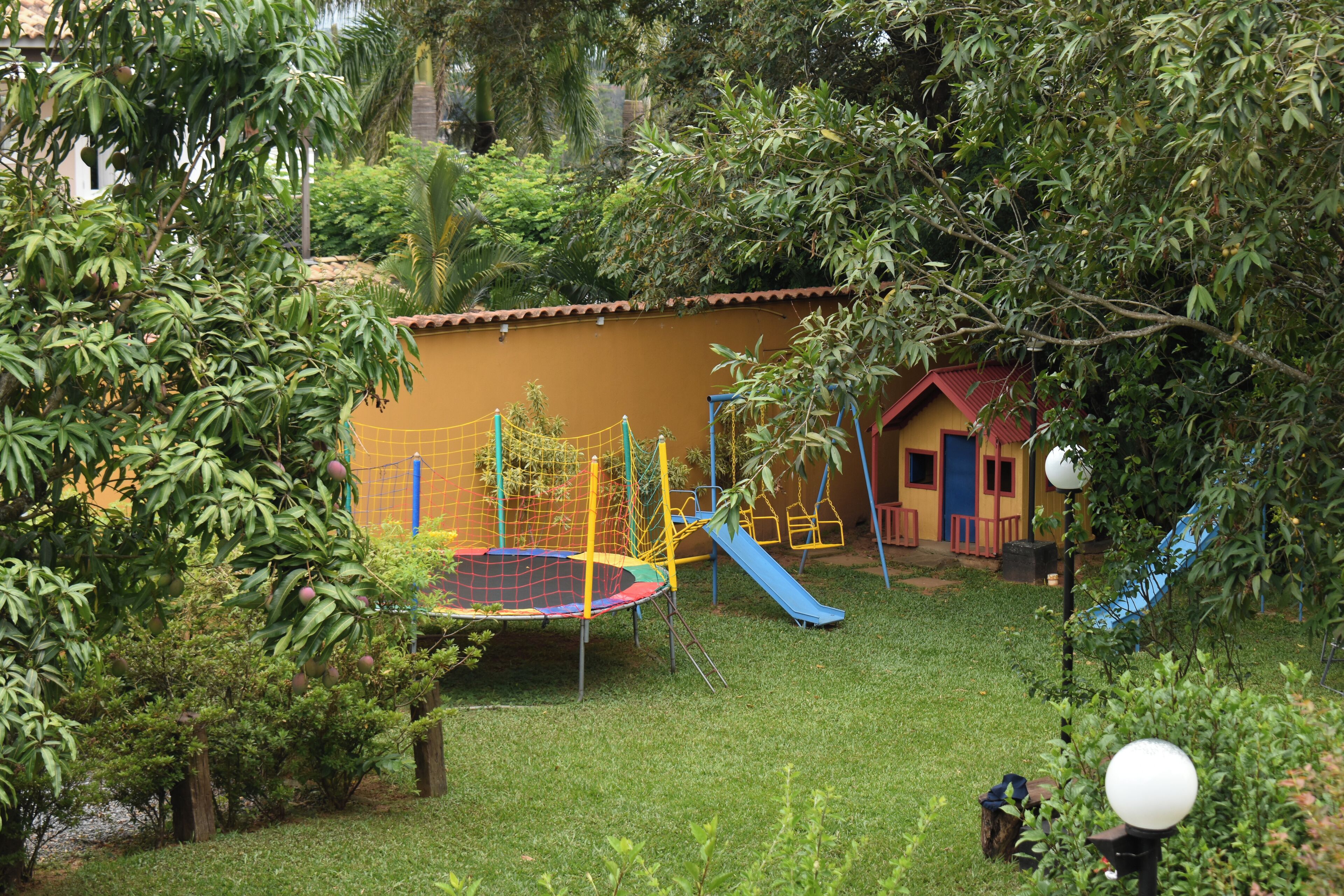 A playground with a trampoline, slide, and climbing net.