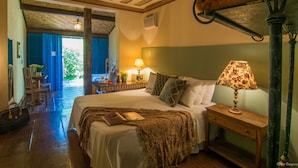 Un dormitorio con cama, mesita de noche, lámpara y vistas al exterior.