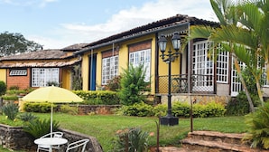 Una casa con un patio que tiene una mesa, sillas, un paraguas amarillo y un camino de piedra.