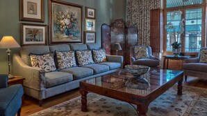 A living room with a sofa, armchairs, a coffee table, and a large window with curtains. - Maison Fougere (Franschhoek)