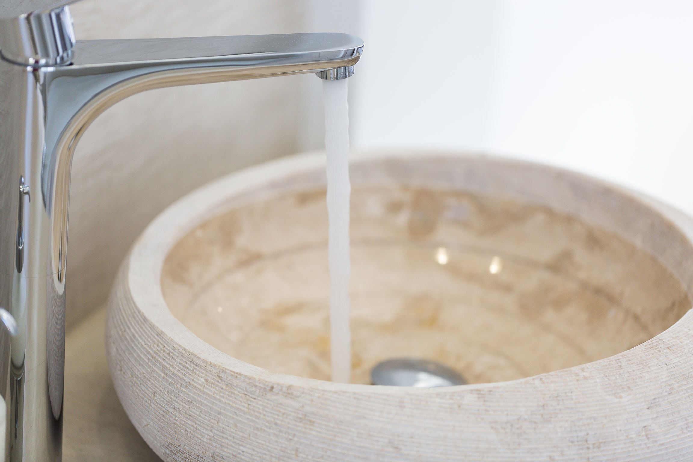 A bathroom sink with a wooden basin and a modern faucet.