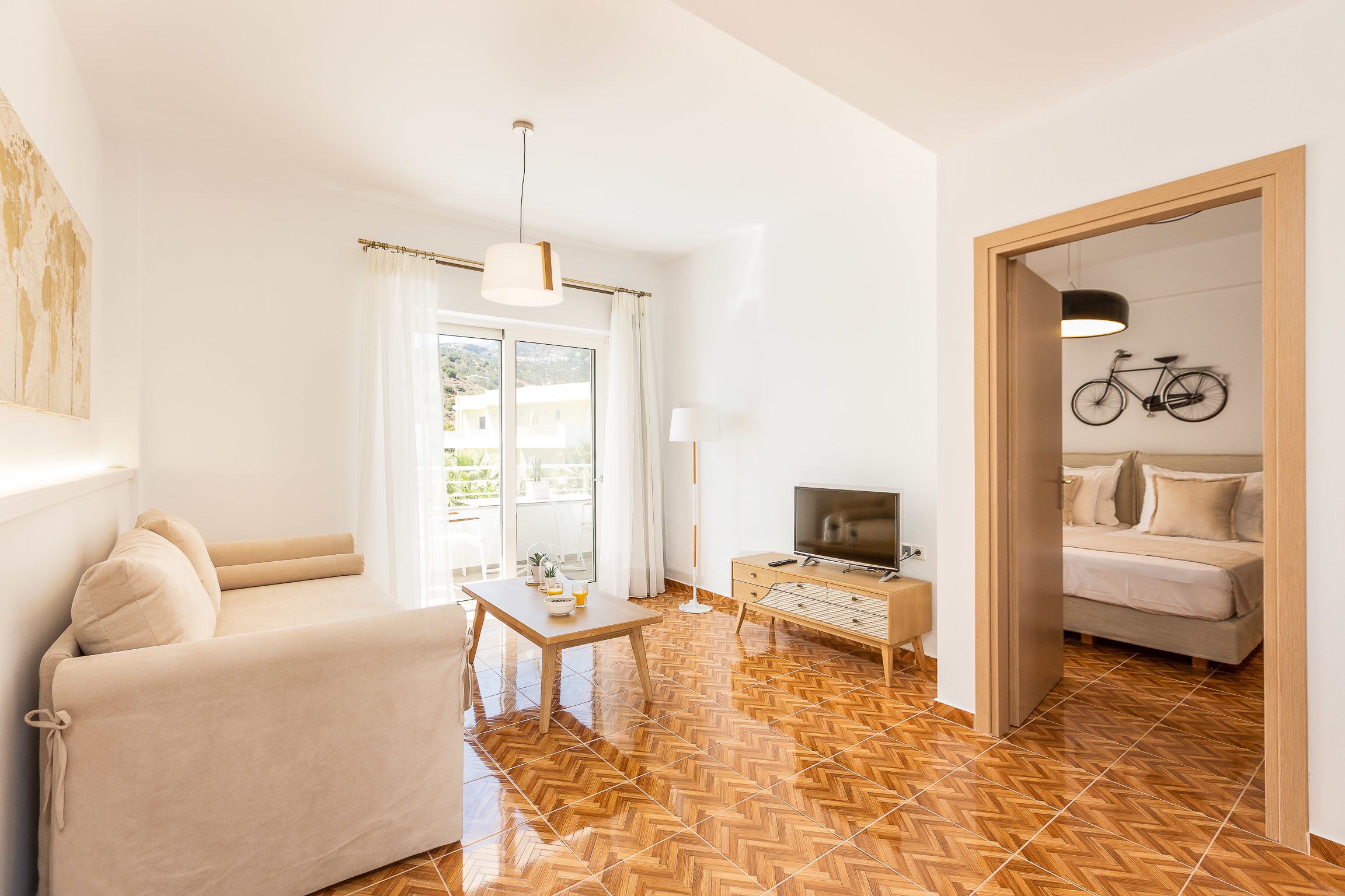 A modern living room with a sofa, a coffee table, a TV, and a bicycle wall-mounted.