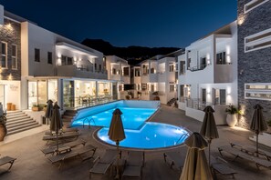 A modern hotel with a central swimming pool, multiple balconies, and outdoor seating areas. - Cyano Hotel (Agios Vasileios)