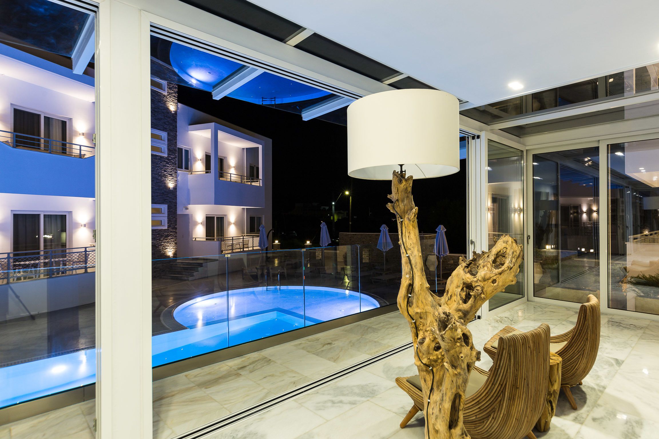 A modern building with a pool, large windows, and a unique wooden sculpture.