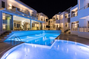 A modern hotel with a swimming pool, multiple balconies, and a well-lit exterior. - Cyano Hotel (Agios Vasileios)