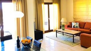 A modern living room with a glass dining table, a sofa, and a coffee table. - Angelos Junior Villa with pool HG22 (Kouklia)