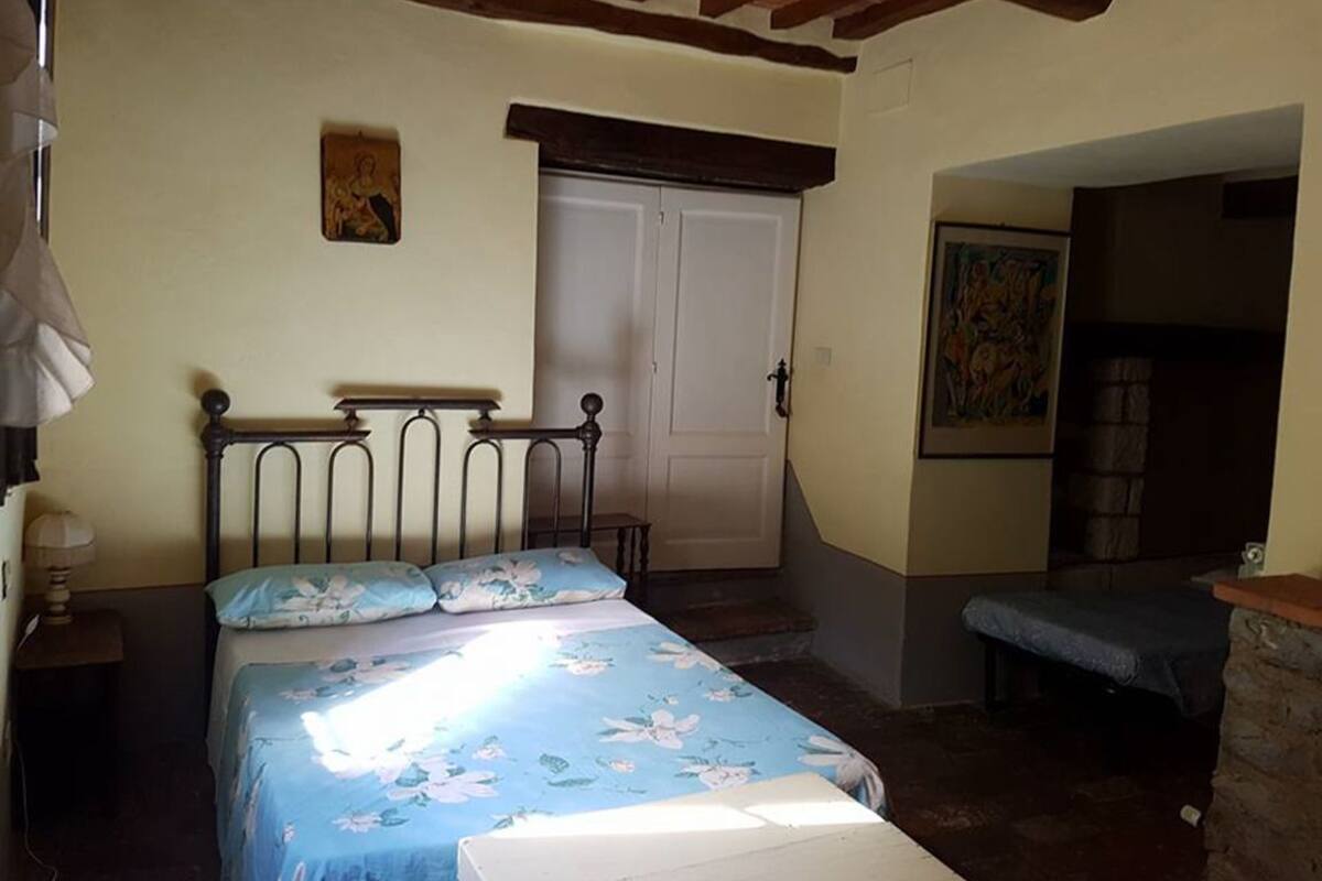 A bedroom with a bed, a nightstand, a door, and a painting on the wall.