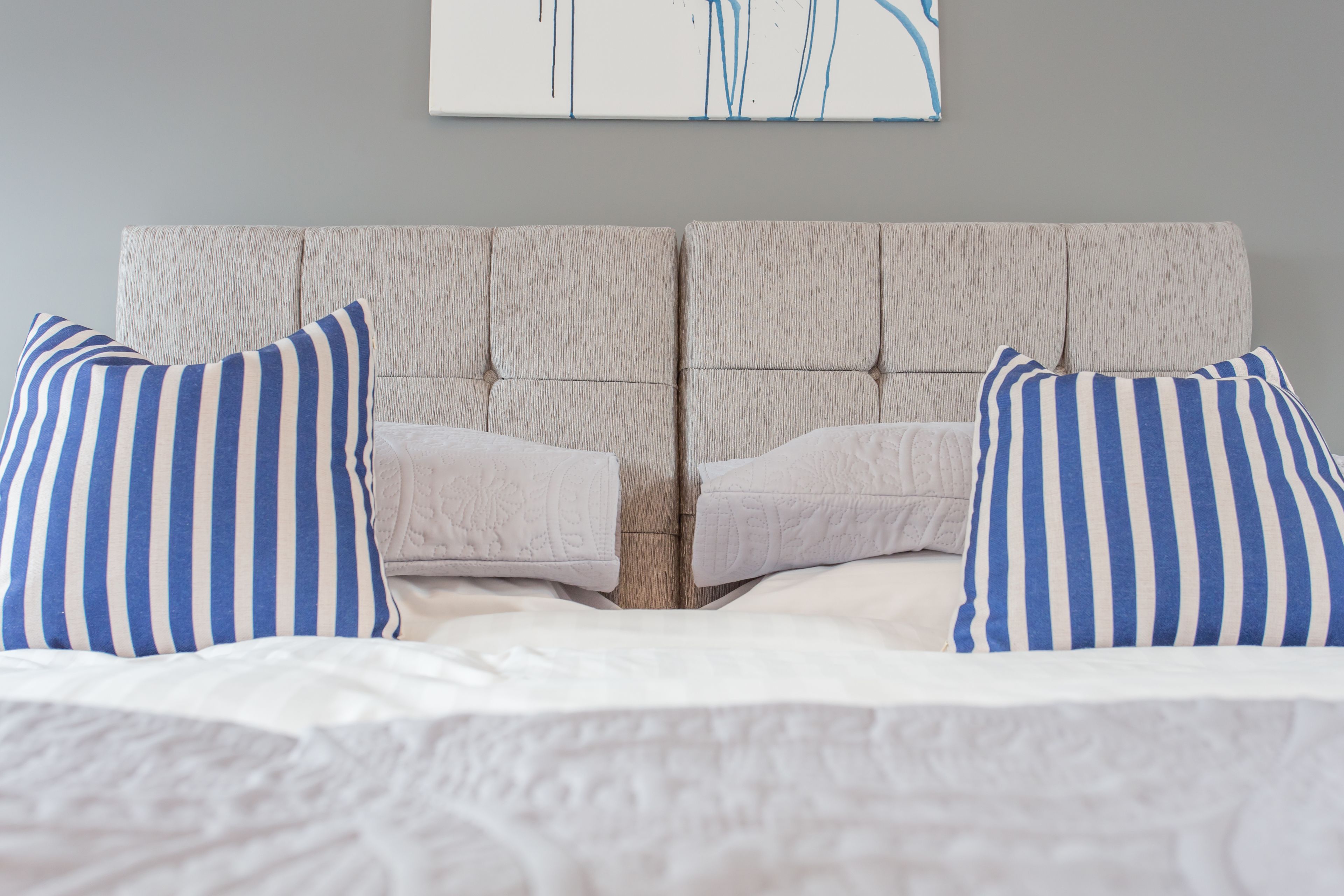 A bed with a tufted headboard, two pillows, and a white bedspread.