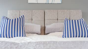 A bed with a tufted headboard, two pillows, and a white bedspread.
