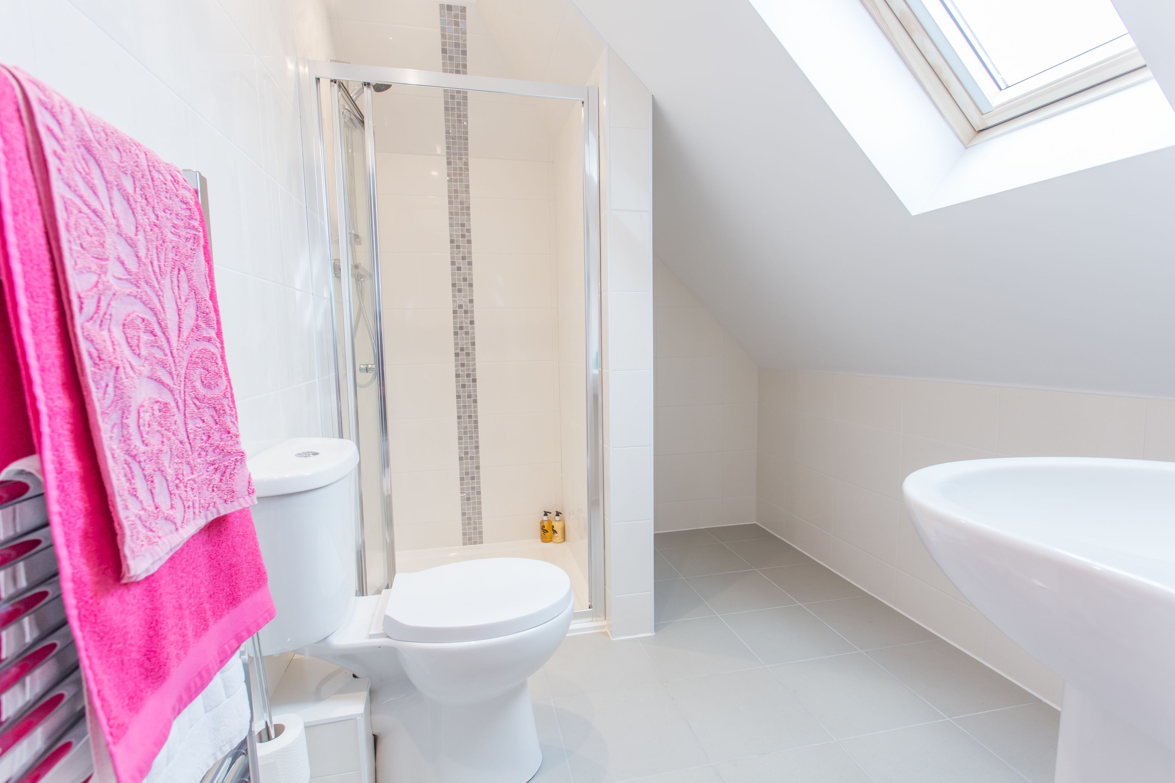 Ein modernes Badezimmer mit Oberlicht, Dusche, Toilette und Badewanne.