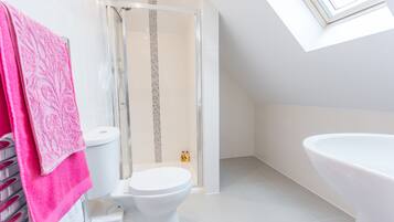 Ein modernes Badezimmer mit Oberlicht, Dusche, Toilette und Badewanne.