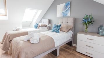 Una camera da letto moderna con due letti, un lucernario, un grande quadro astratto e un vaso con fiori.
