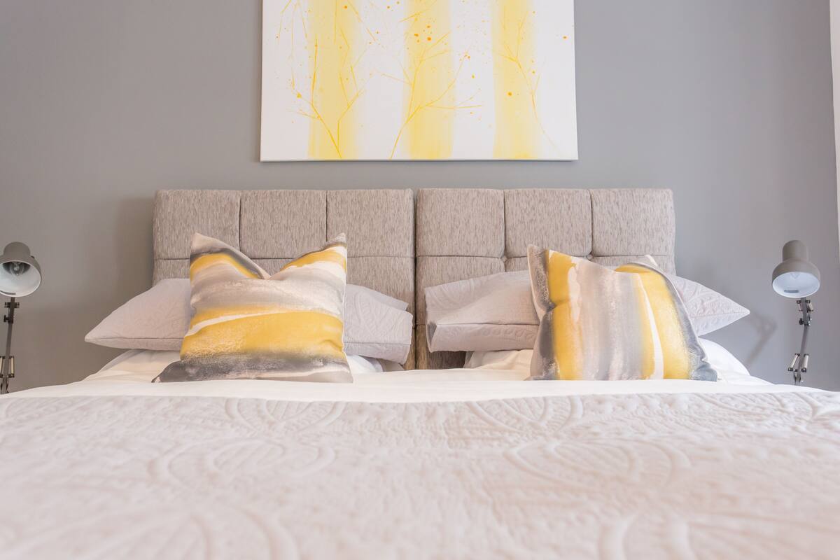 A neatly made bed with patterned bedding, two bedside lamps, and a wall-mounted artwork.
