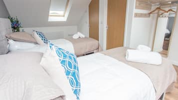 Un dormitorio moderno con dos camas, un tragaluz, un armario de madera y un espejo.