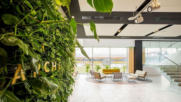 A modern lobby with a green wall, seating area, and a view of the outside. - Arche Hotel Krakowska (Warsaw)