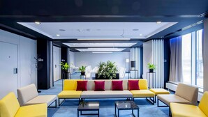 A modern lobby with a sofa set, two armchairs, a coffee table, and potted plants. - Arche Hotel Krakowska (Warsaw)