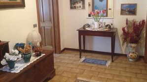 A hallway with a wooden door, a small table with a vase of flowers, and a wall decorated with framed pictures. - B&B Relax (Miane)