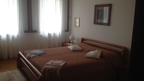 A bedroom with a wooden bed, white curtains, a bedside table with a lamp, and a framed picture on the wall. - B&B Relax (Miane)