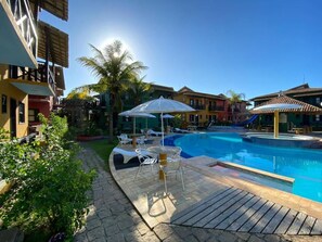 A swimming pool with lounge chairs and umbrellas, surrounded by buildings with balconies. - Costa Marlin Hotel (Sao Mateus)