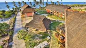 A resort with thatched-roof buildings, a beach path, and palm trees. - Carnaubinha Praia Resort (Luis Correia)